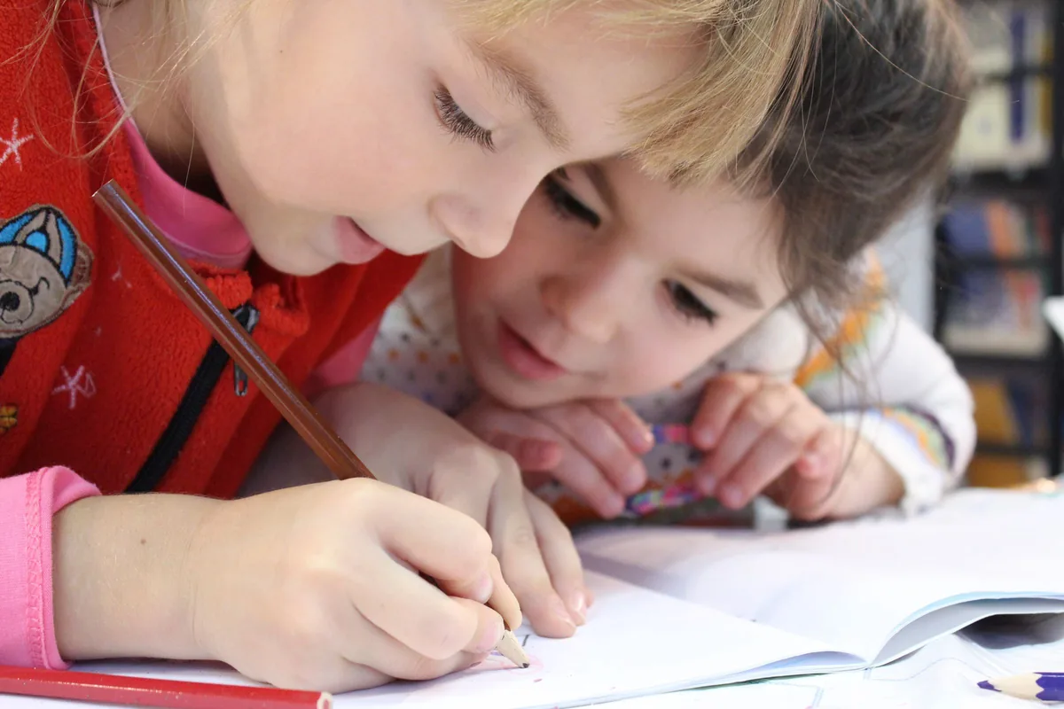 Two children drawing together at a table